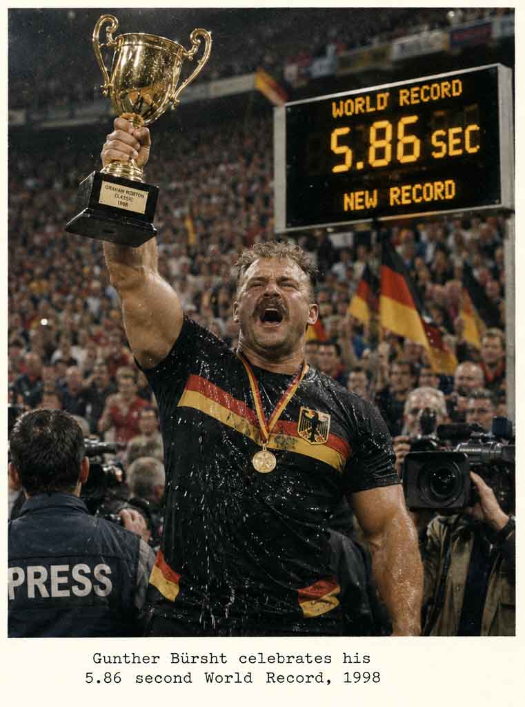 Gunther Bürsht celebrates his 5.86-second Peeball world record in 1998, holding the trophy aloft in front of a cheering crowd.